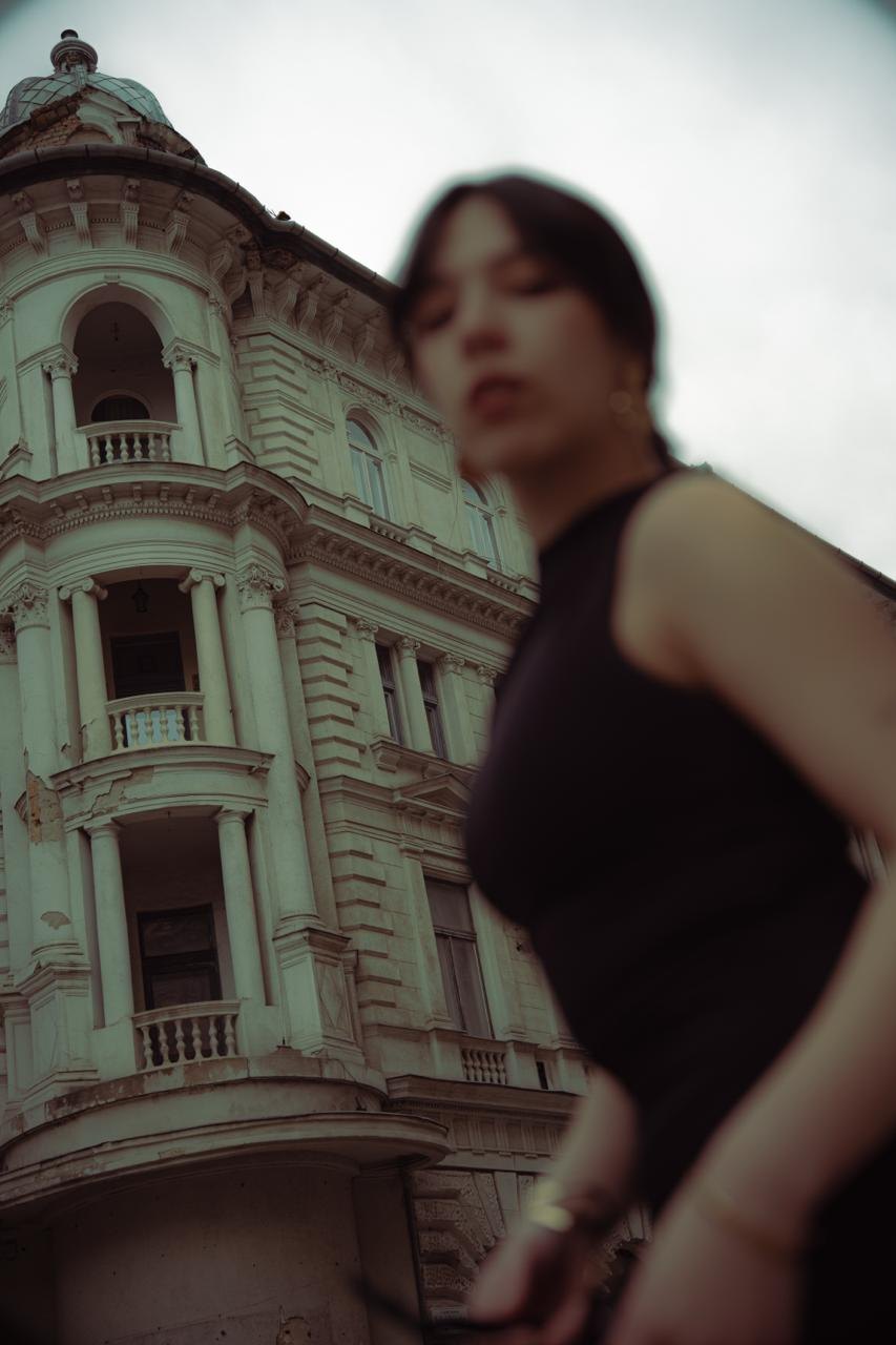 A woman in a dark top in front of an ornate building, the frame tilted