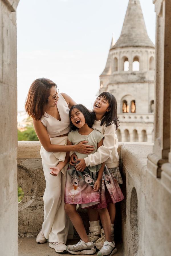 A mother and her two daughters laughing together on a balcony of Fisherman's Bastion