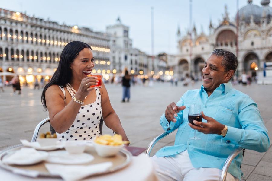 A couple toasting at a café table in St Mark's Square at dusk