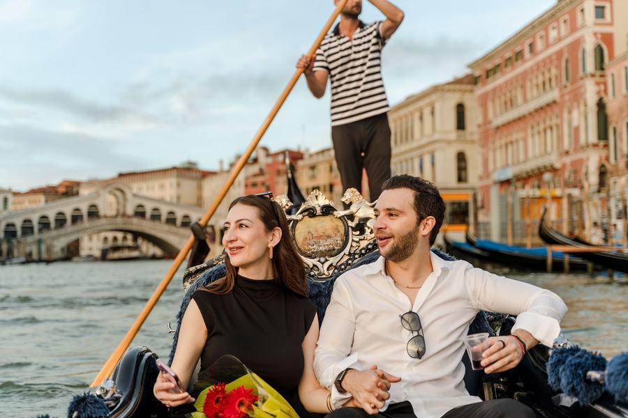 A couple on a gondola on the Grand Canal, the Rialto Bridge behind them