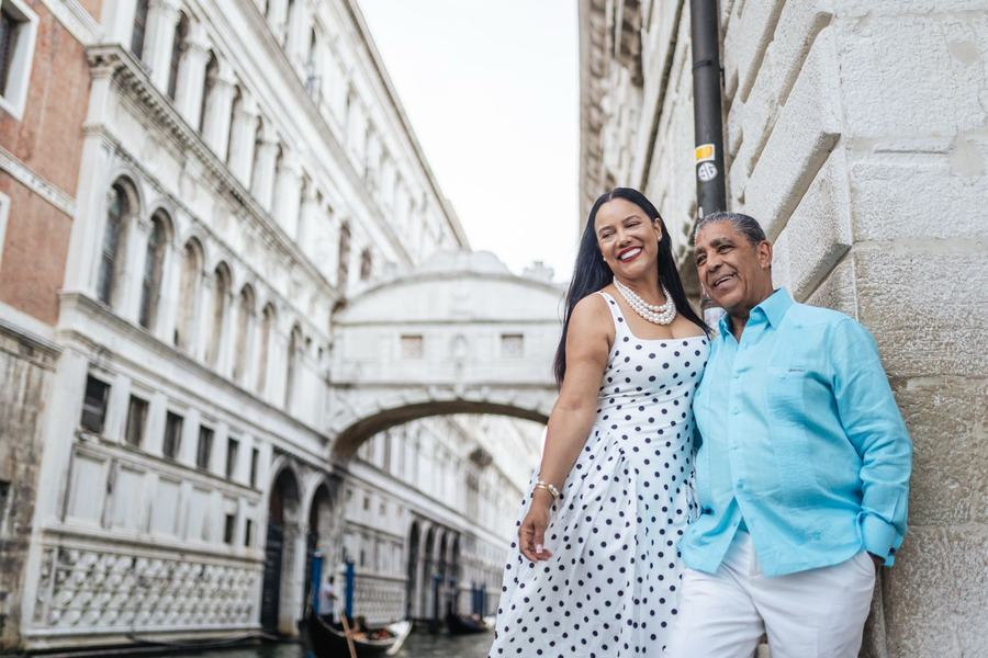 A laughing couple leaning on a wall by the canal below the Bridge of Sighs