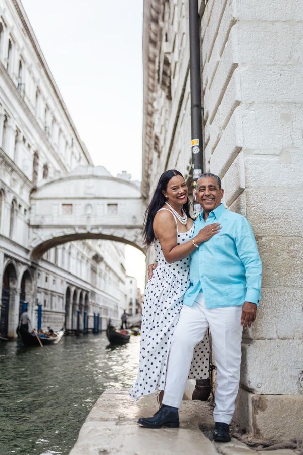 A smiling couple on the canal edge below the Bridge of Sighs