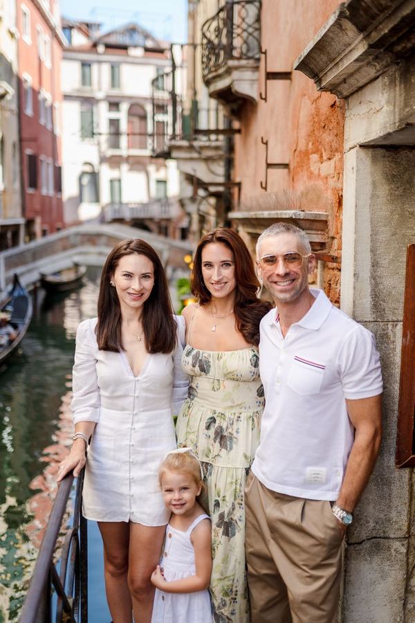 Two women, a man and a little girl smiling by a canal in Venice