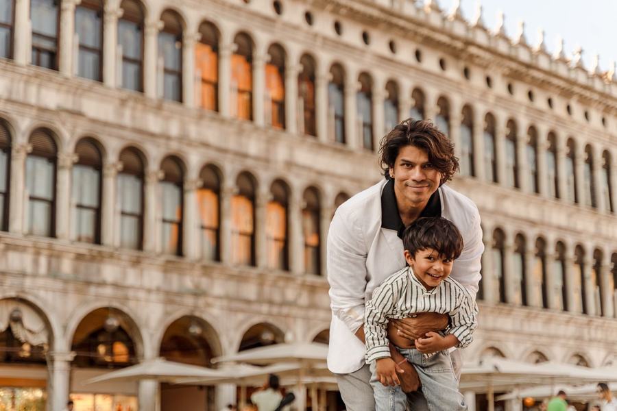 A father lifting his laughing son in St Mark's Square