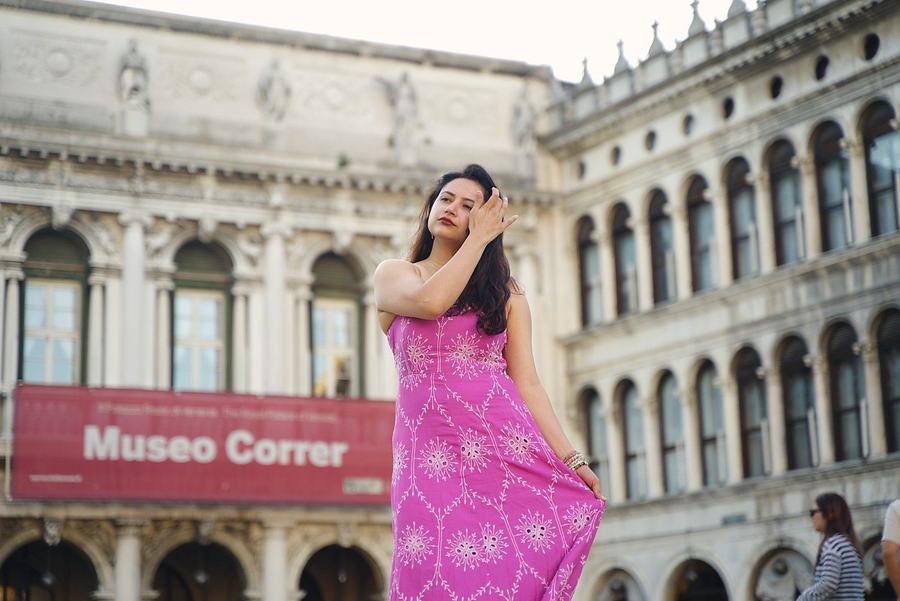 A woman in a pink dress posing in St Mark's Square in front of the Museo Correr